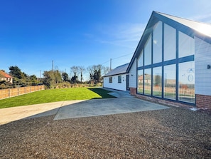 A modern building with large windows, a paved driveway, and a well-maintained lawn. - 3 bedroom accommodation in Sidestrand (Sidestrand)