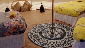 A tent with two beds, each with a patterned bedspread and pillows, and a central pole. - Beautiful Idilic Stay at The Box (Chichester)