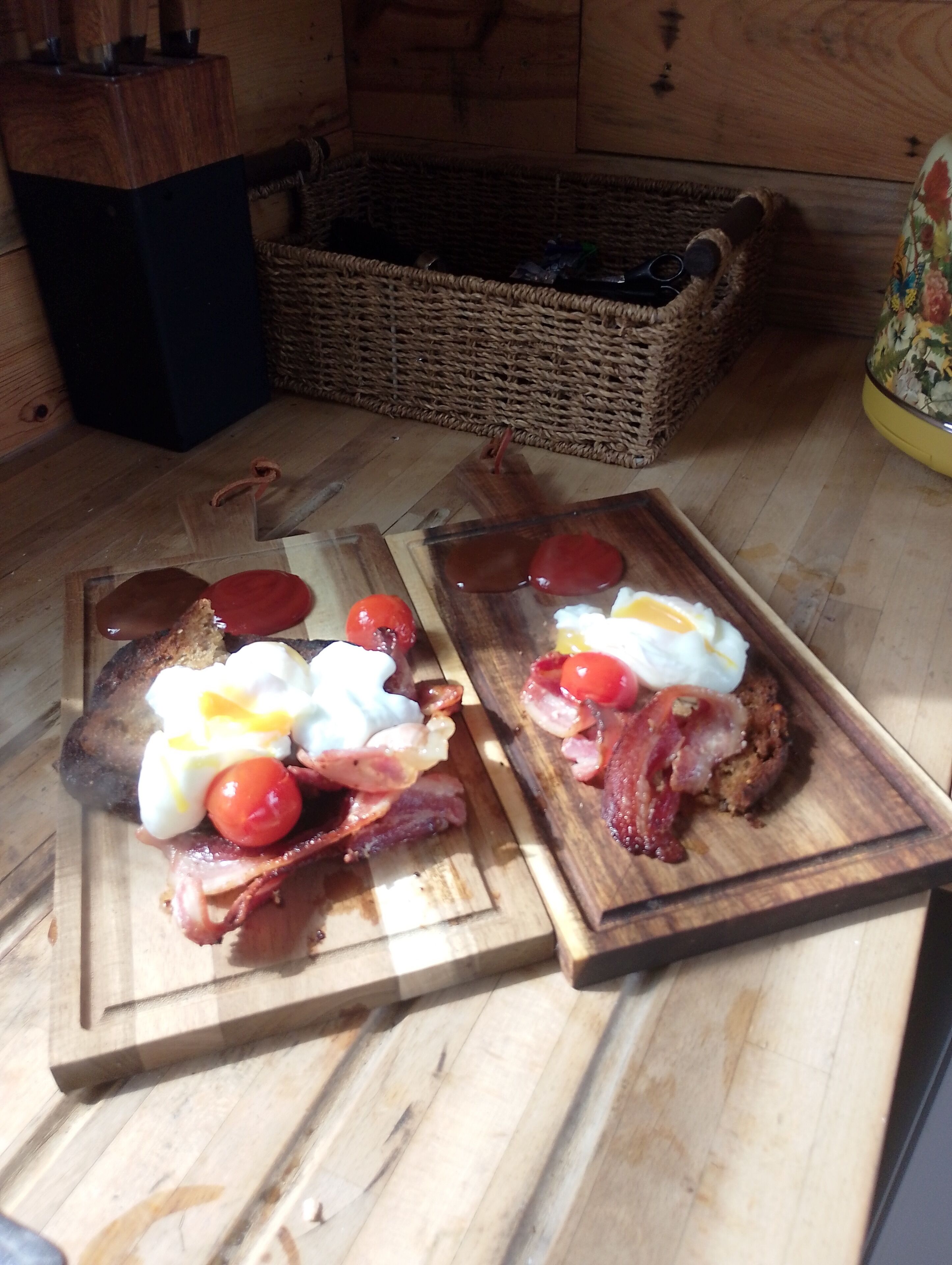 Two wooden cutting boards with breakfast items on a wooden floor.