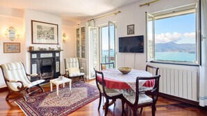 A dining area with a table, chairs, a fireplace, and a view of the sea. - 3 bedroom awesome apartment in Zoagli (Zoagli)