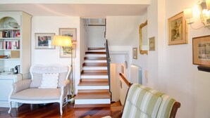 A staircase leading to a second floor, a white armchair, a striped armchair, a bookshelf, and wall-mounted artwork. - 3 bedroom awesome apartment in Zoagli (Zoagli)