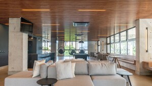 A spacious lounge area with a large sectional sofa, a pool table, and a hanging chair. - LIV by LEMMON HOMES (Porto Alegre)
