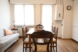 A dining area with a table, chairs, a basket, and a sofa.