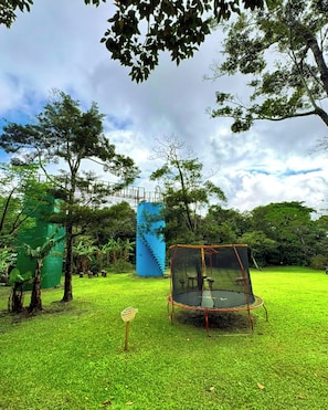 A grassy area with a trampoline and a blue staircase structure.