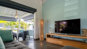 Una sala moderna con un televisor de pantalla plana grande, sofás grises y un mueble de entretenimiento de madera.