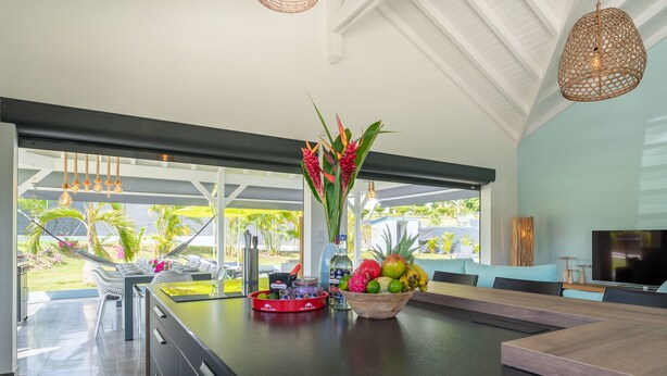 Una cocina moderna con una isla grande, un comedor con televisor y vistas al exterior.