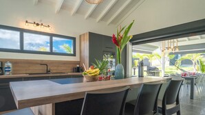 Una cocina moderna con una isla grande, taburetes de bar y vistas al exterior.