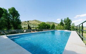 A rectangular swimming pool with a clear blue water, surrounded by a wooden fence, and a view of a hilly landscape in the background. - Cozy home in La Puebla de los Infan (La Puebla de los Infan)