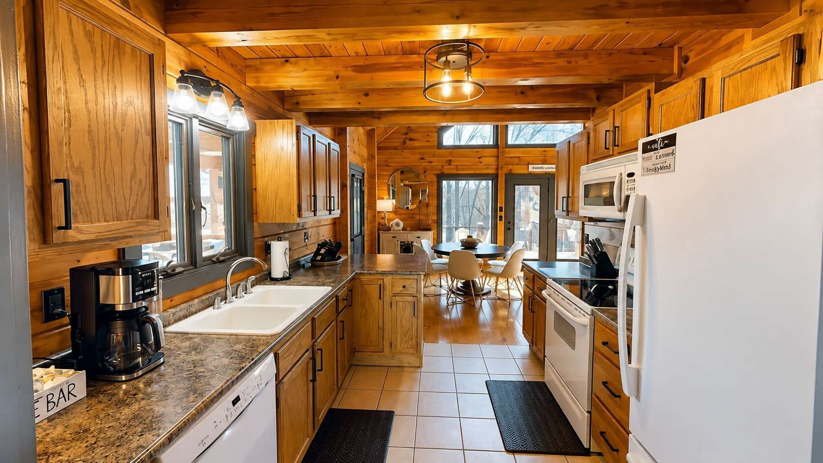 Eine Küche mit Holzschränken, einer Kaffeemaschine, einem Spülbecken, einem Essbereich mit Stühlen und einem Kühlschrank.