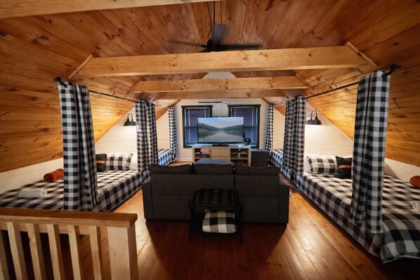 Un chalet confortable avec un coin salon central, un téléviseur et des rideaux à carreaux.