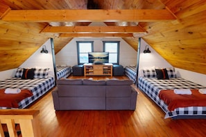 A cozy attic room with a sofa, two beds, a TV, and a wooden ceiling. - Ridge Hideaway • Cozy Lakefront Escape (Cadiz)