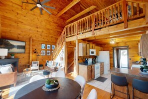 L’intérieur d’une cabane en bois comprend un espace repas, une cuisine et une chambre à coucher située en mezzanine.