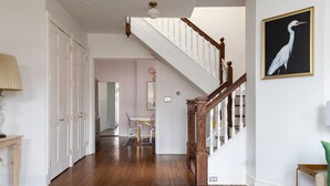 Ein geräumiger Korridor mit Holzboden, einer Treppe mit weißen Stakobel und einem gerahmten Gemälde an der Wand.