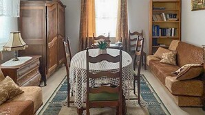 Una sala de estar con una mesa redonda de madera, sillas, un sofá, una estantería y una lámpara.