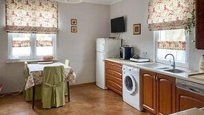 Cocina compacta con lavadora, refrigerador y comedor con mesa y sillas.