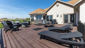 Een terras met tuinmeubilair, een barbecuehoek en een overdeeld gedeelte met een tafel en stoelen.