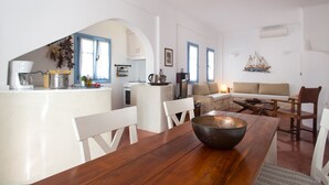 A compact living space with a kitchen, dining area, and seating area. - Daphne | Cycladic Three-Bedroom Villa with Private Pool and Sea View (Thira - Santorini)