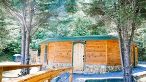 Une cabane en bois avec des fondations en pierre, une porte en bois et une enseigne sur laquelle on peut lire : « Chez maman ».