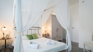 Quarto com cama de dossel, mesas de cabeceira, aparador e uma cadeira.