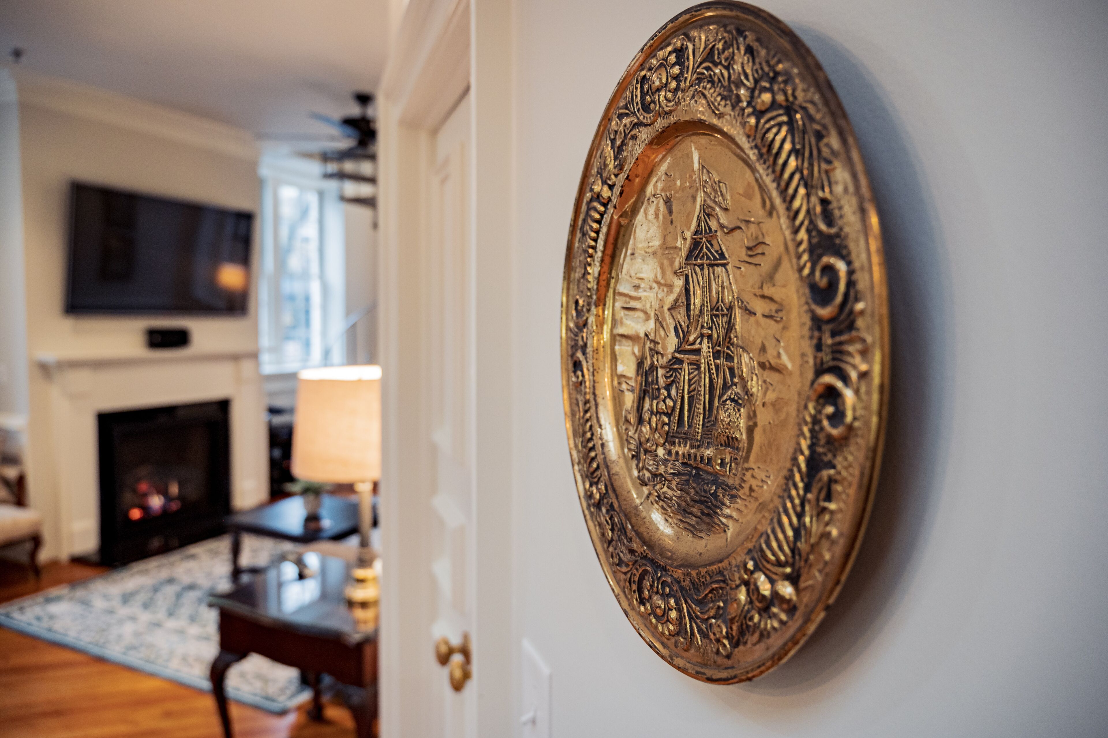 A room with a fireplace, a television mounted on the wall, and a decorative plate on the wall.