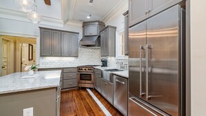 A modern kitchen with stainless steel appliances, grey cabinets, and a wooden floor.