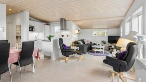 Una sala de estar moderna con comedor, cocina y televisor.