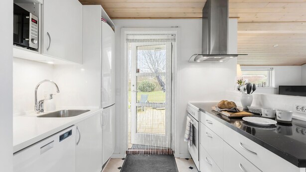 Una cocina moderna con armarios blancos, un lavamanos de acero inoxidable, un microondas y una estufa.