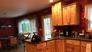 Una cocina con armarios de madera, cafetera y un comedor con mesa y sillas.