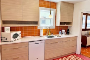 A modern kitchen with wooden cabinets, a built-in microwave, a sink, and a window above the countertop.