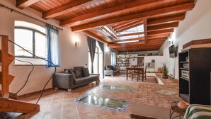 A spacious living area with a high wooden ceiling, a fireplace, a sofa, and a dining table. - Amazing home in Trappeto with house sea view (Trappeto)