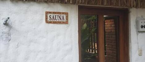 Edificio con un letrero que dice "SAUNA" sobre una puerta de madera.
