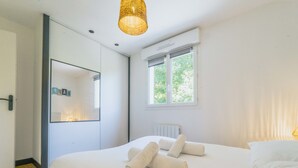 A modern bedroom with a large bed, a mirror, a window, and a ceiling light fixture. - Le Tarnosien - Landes - Côte Basque (Tarnos)