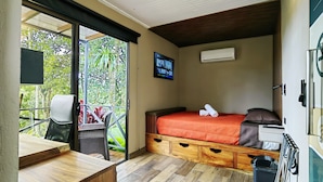 A bedroom with a bed, a TV, and a sliding glass door leading to a balcony.