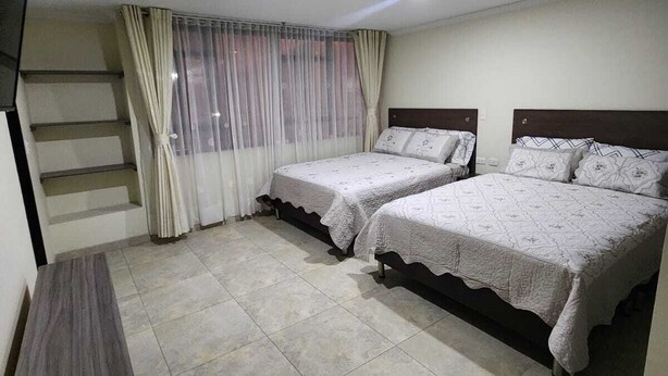 A bedroom with two beds, a TV, and a staircase. - Casa Hotel Mared (Bogotá)