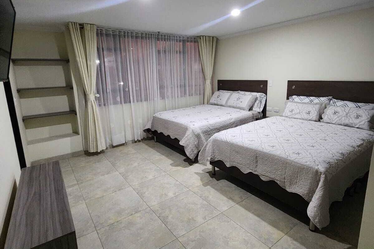 A bedroom with two beds, a TV, and a staircase.