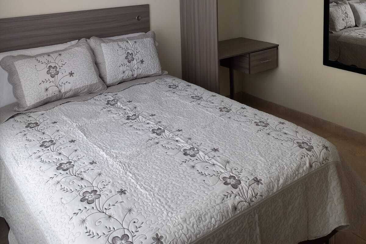 A bedroom with a bed, a dresser, a mirror, and a hanging closet.