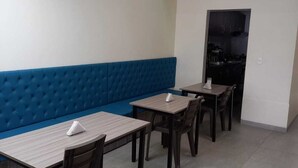 A dining area with a blue cushioned bench, wooden tables, and chairs. - Casa Hotel Mared (Bogotá)