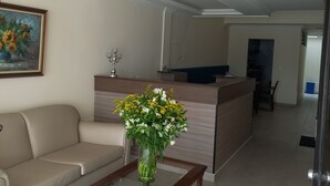 A modern living room with a sofa, a coffee table with a vase of flowers, a painting on the wall, and a kitchen area in the background. - Casa Hotel Mared (Bogotá)