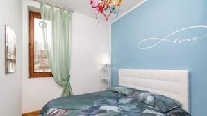 Un dormitorio con una cama, una ventana con cortinas, una pared con una palabra y un candelabro.