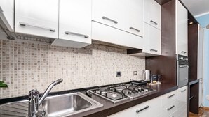Una cocina moderna con armarios blancos, un lavamanos de acero inoxidable y una estufa a gas.