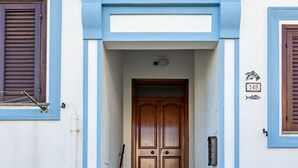 Une entrée d’immeuble avec une porte en bois, des bordures bleues et une enseigne portant un numéro.