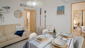 A dining area with a table set for four, a hanging light fixture, and a wooden door leading to another room. - GuestHost - Spacious and elegant, finely renovated apartment capable of accommodating up to 6 people, located on the ground floor of a typical ligurian building in the center of Sanremo, a few steps from the famous Casino. Nearby is Via Matteotti, with i (Sanremo)