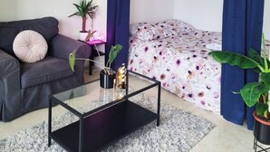Un dormitorio moderno con una cama, un sofá, una mesita de café y una planta en maceta.