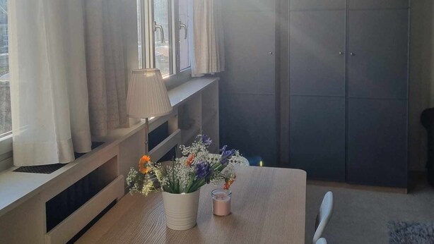 Una habitación moderna con una mesa de madera, una lámpara y un florero con flores.