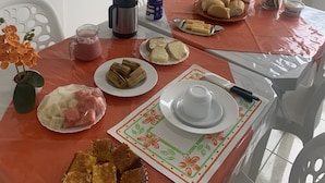 Una mesa de comedor con diferentes alimentos, una botella de agua, una cafetera y un jarrón con flores.