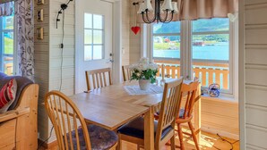 A dining area with a wooden table, chairs, and a view of a lake through large windows.