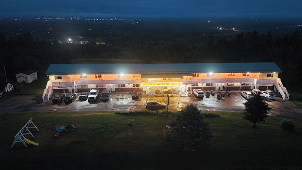 A motel with a large parking lot, multiple vehicles, and a well-lit exterior. - Scenic Motel Moncton  (Berry Mills)