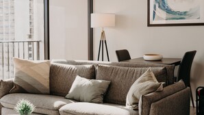 Ein modernes Wohnzimmer mit einer Couch, einer Stehlampe und einem gerahmten abstrakten Gemälde an der Wand.