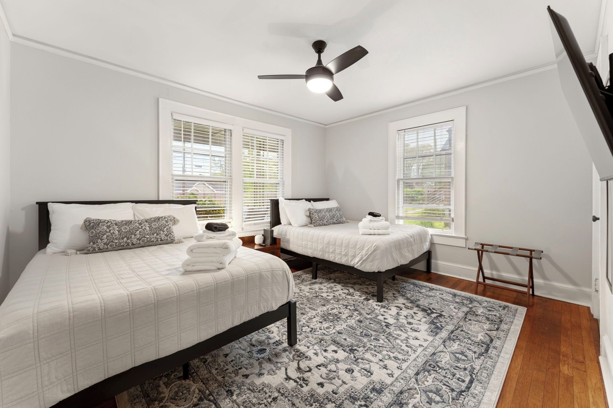Une chambre avec deux lits, un ventilateur de plafond et un tapis à motifs.