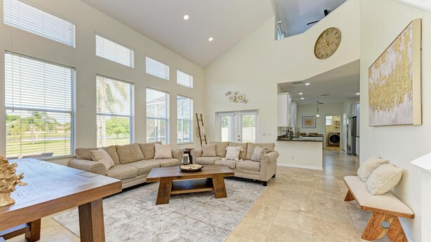 A spacious living room with a large sectional sofa, a wooden coffee table, and a dining table.